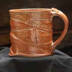 Rust-glazed stoneware mug with carved motif
